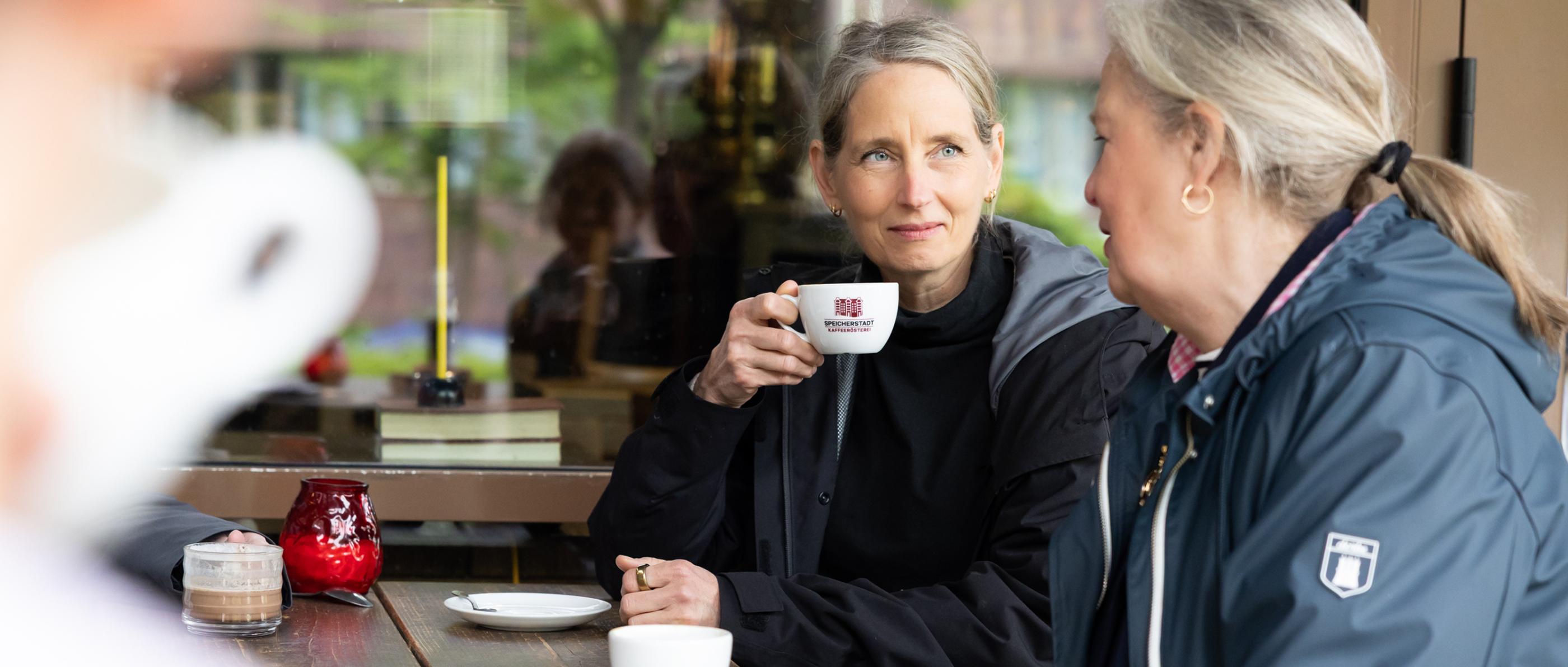Ehrenamtliche trinken Kaffee und unterhalten sich.