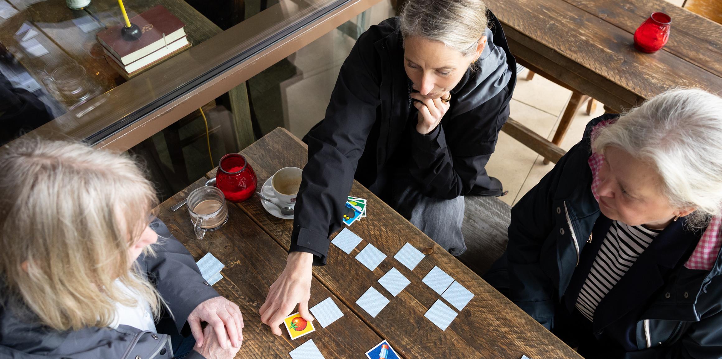 Von oben fotografiert. Drei Frauen spielen Memory.