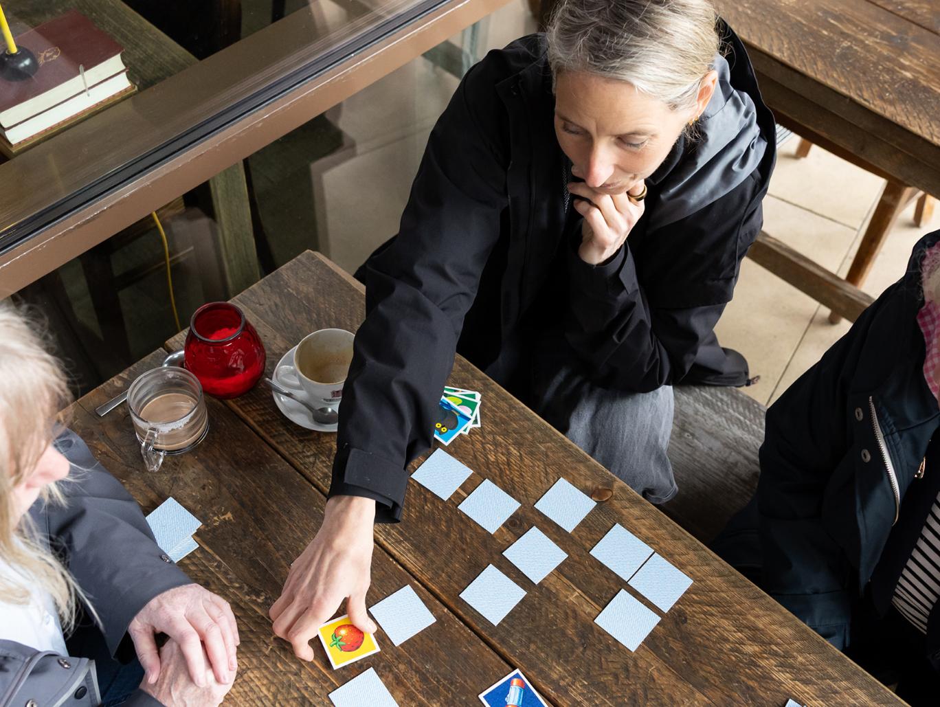 Von oben fotografiert. Drei Frauen spielen Memory.