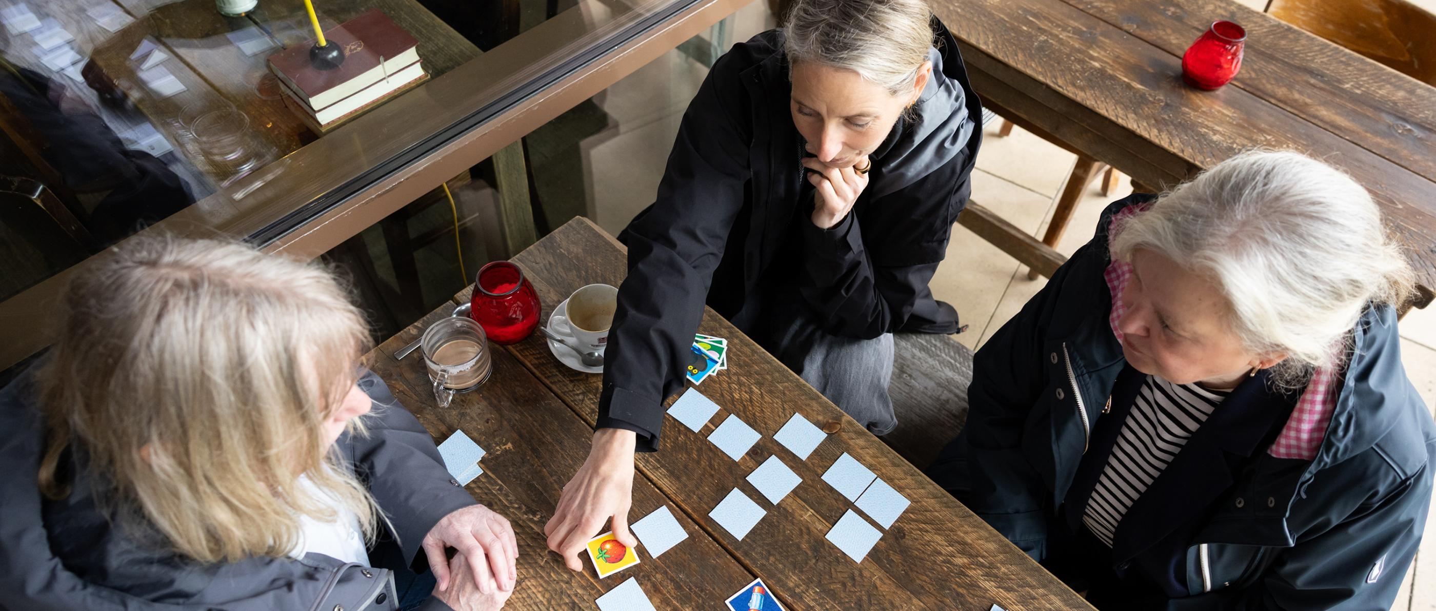 Von oben fotografiert. Drei Frauen spielen Memory.