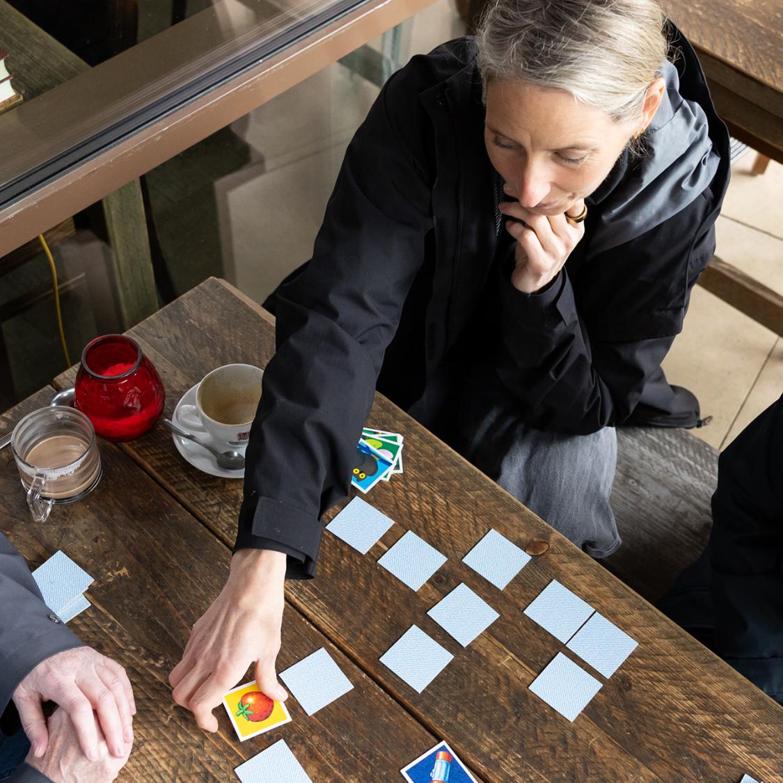 Von oben fotografiert. Drei Frauen spielen Memory.