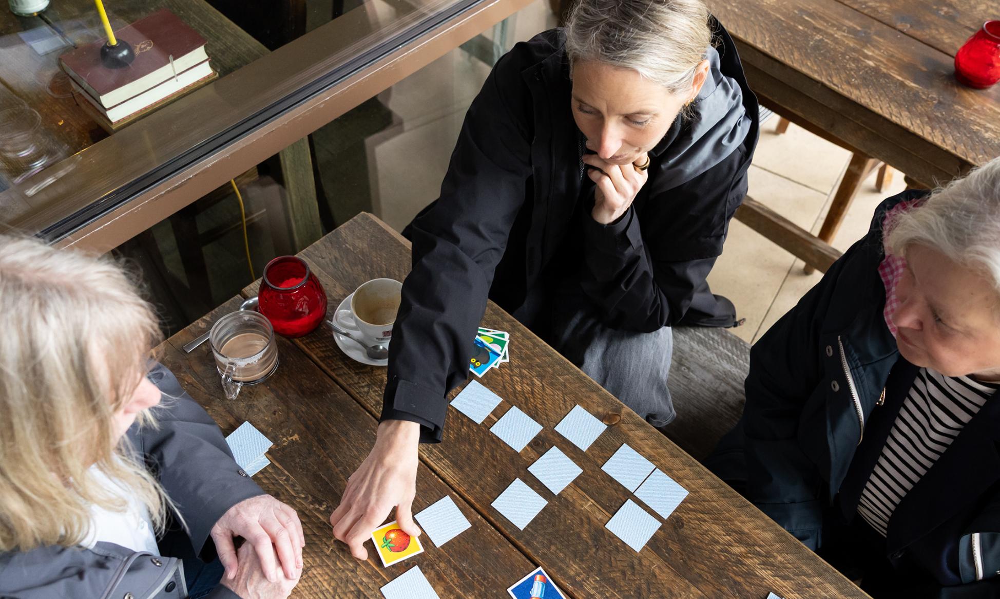 Von oben fotografiert. Drei Frauen spielen Memory.